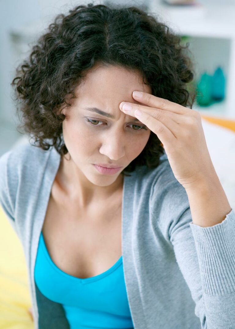a woman presses her fingers to her forehead for a headache pain maybe TMD/TMJ related