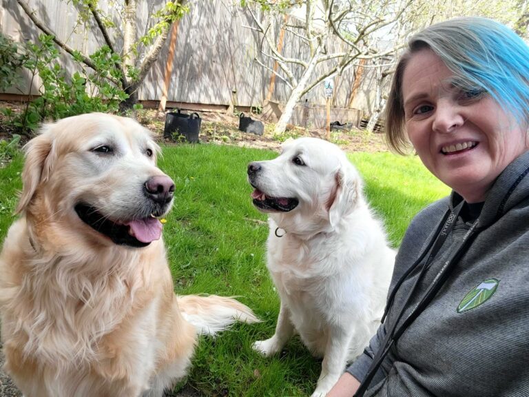 woman and her dogs in a grassy parklike setting smiling for the camera