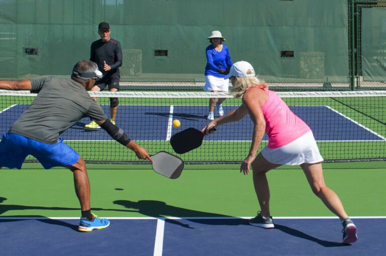 two middle aged couples compete on the pickleball court