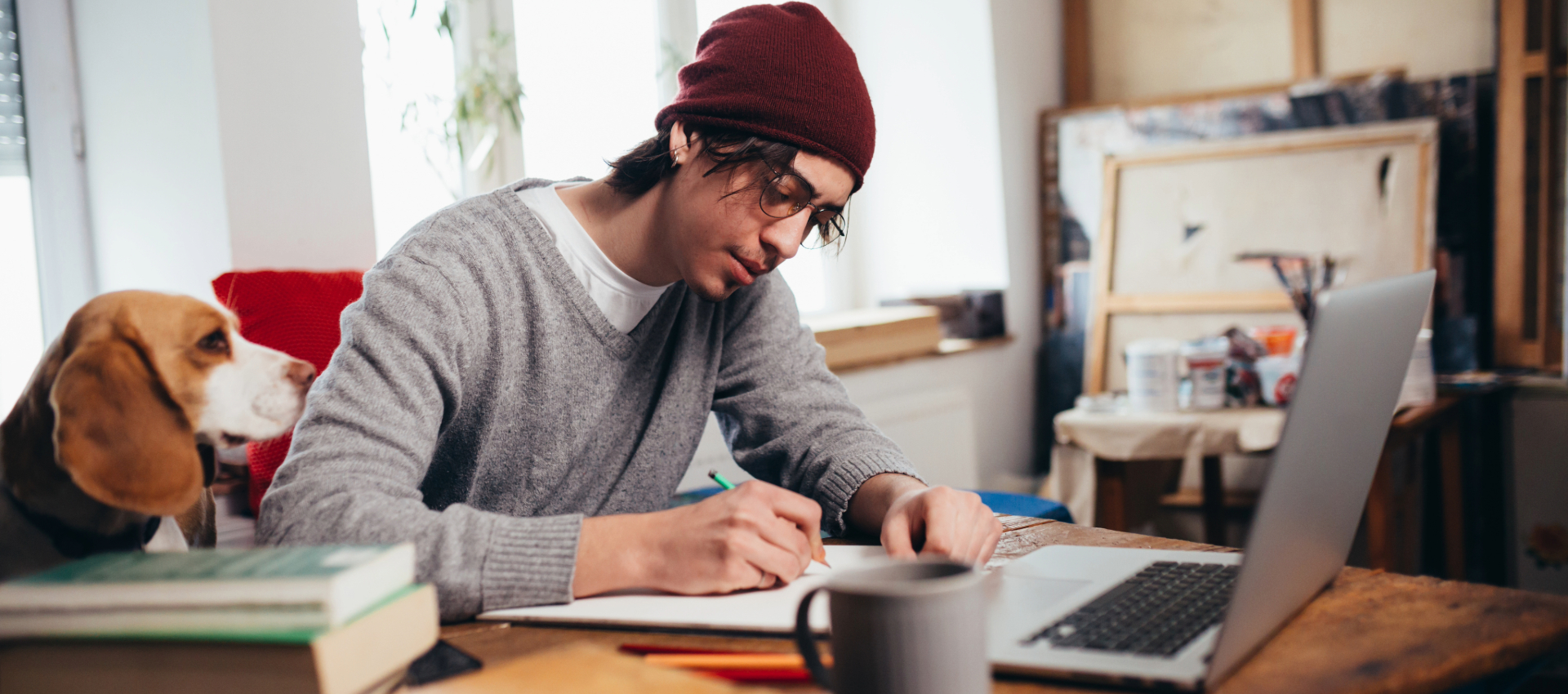 a young man working from home on his computer while hunched over a table with poor posture